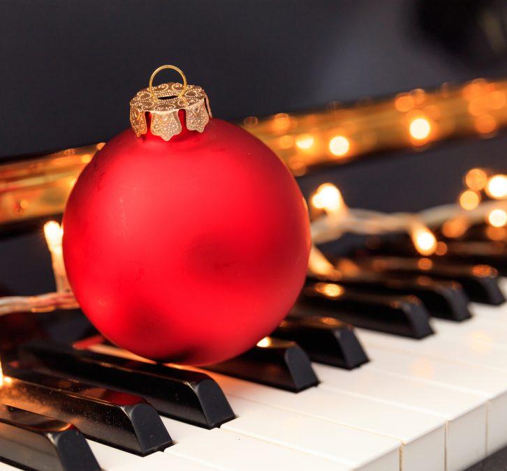 Zdjęcie przedstawia bombkę świąteczną na klawiaturze fortepianu.